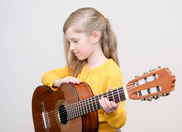 Pretty little girl playing acustic guitar - Фото, изображение