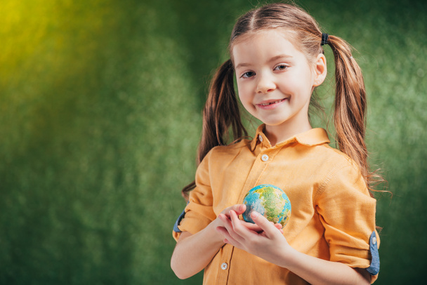 aranyos mosolygós gyermek gazdaság világon modell szív közelében elmosódott háttér, föld napja koncepció - Fotó, kép
