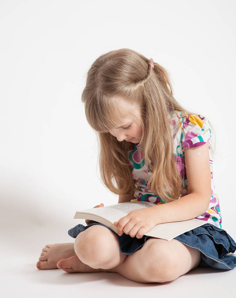 Pretty little girl reading a book, white background - Fotó, kép