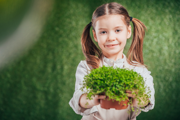 Cute usmívající se dítě drží Květináč s rostlinou na rozostřeného pozadí, koncept den země - Fotografie, Obrázek