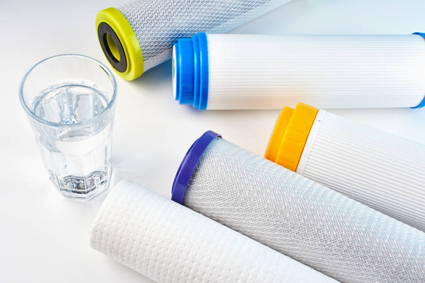 Water filters. Carbon cartridges and a glass on a white background. Household filtration system. - Foto, imagen