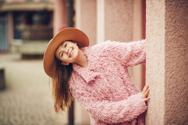 Outdoor fashion portrait of young girl wearing pink faux fur coat, street style  - Photo, Image