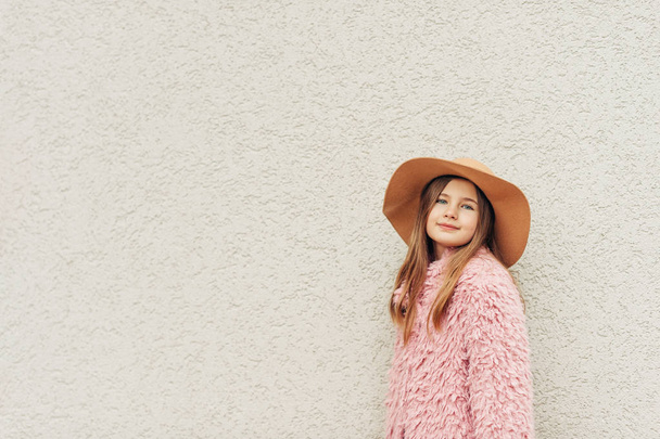 Csinos, fiatal gyerek lány visel, barna kalapot és rózsaszín kabát, utcai divat a gyermekek számára szabadtéri portréja - Fotó, kép