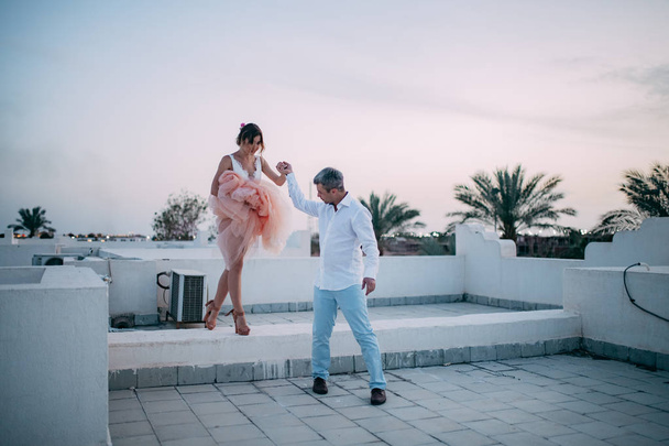Happy newlyweds walk on roof of house during the honeymoon in Egypt in the evening. - Valokuva, kuva