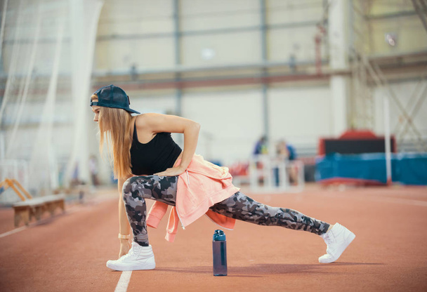 Young beautiful woman with blonde hair stretching in the sports hall - Photo, Image