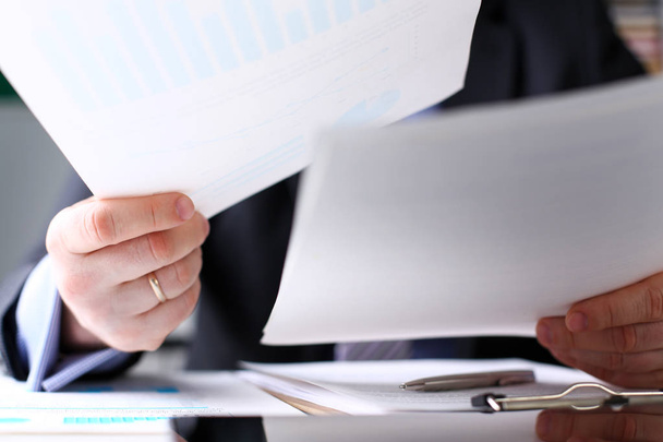 Brazo de empleado masculino examinar documentos financieros importantes en el lugar de trabajo
 - Foto, Imagen