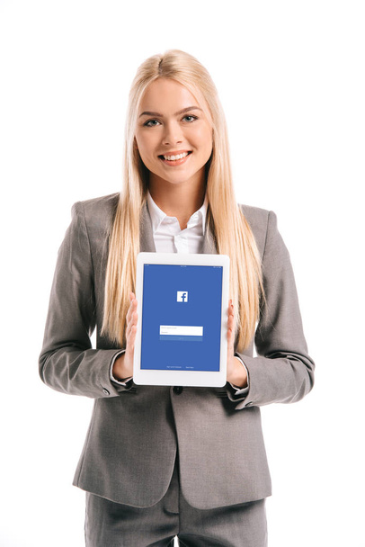 beautiful blonde businesswoman showing digital tablet with facebook app on screen, isolated on white - Φωτογραφία, εικόνα