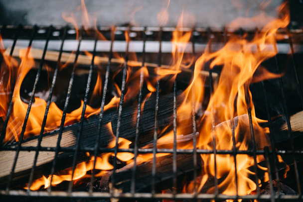 палаючі дрова з полум'ям через решітку гриля барбекю
 - Фото, зображення