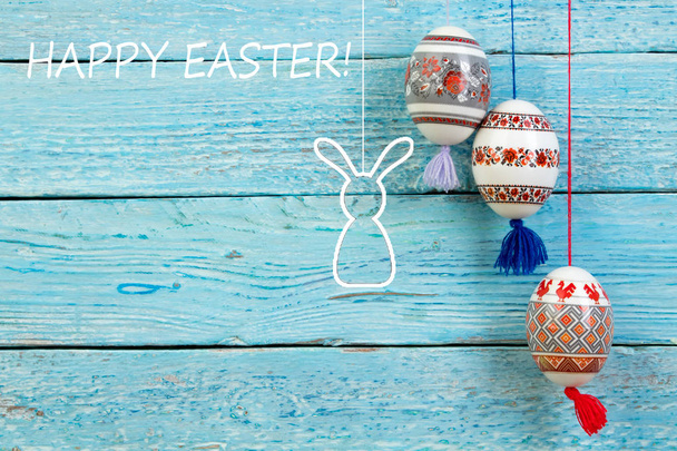 Happy Easter card. Colorful shiny easter eggs and rabbit on blue wooden table background. Copy space for text - Photo, Image