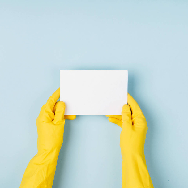 Hands in yellow gloves hold empty card. Cleaning or housekeeping concept background. Copy space. Flat lay, Top view. - Foto, Imagen