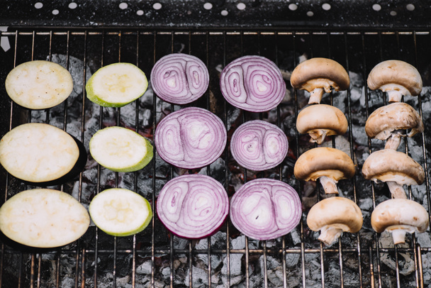 raw eggplant and onion slices, mushrooms, zucchini grilling on barbecue grid - Photo, image