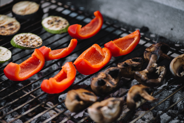 selective focus of red bell pepper, zucchini and mushrooms grilling on barbecue grill grade - Photo, Image