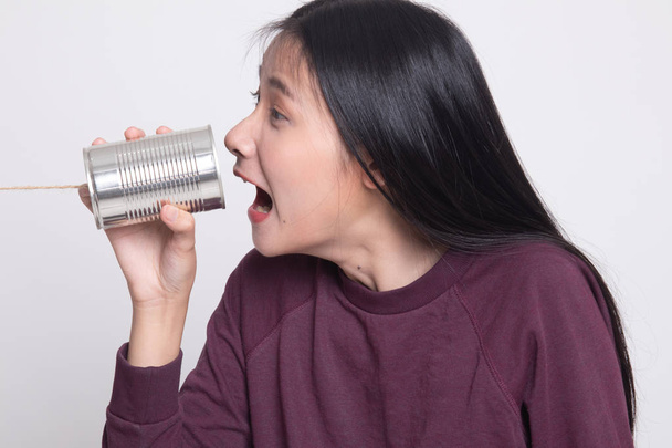 白い背景の上のブリキ缶電話で若いアジア女性の叫び - 写真・画像