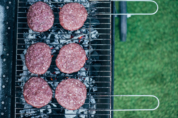 top view of uncooked fresh burger cutlets grilling on bbq grid - Foto, afbeelding