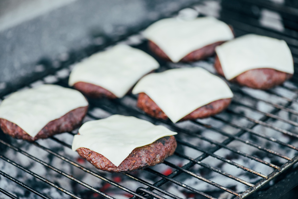 selective focus of fresh burger cutlets with cheese grilling on bbq grid - Foto, Imagem