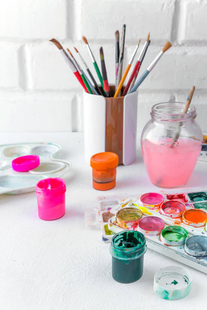 Paper, watercolors, paint brush and some art stuff on wooden table  - Fotó, kép