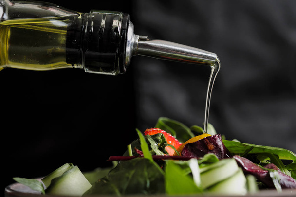 Cooking salad chef in the kitchen of the restaurant. Watering olive oil from the bottle with dispenser. - Foto, Imagem