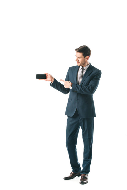 businessman in suit pointing at blank screen on smartphone, isolated on white - Fotoğraf, Görsel