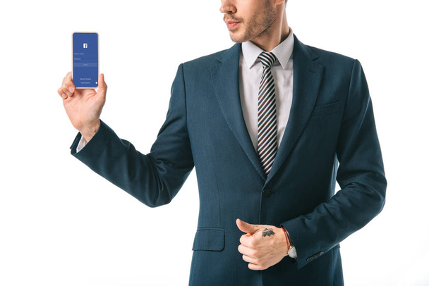 cropped view of businessman showing smartphone with facebook app, isolated on white - Fotó, kép