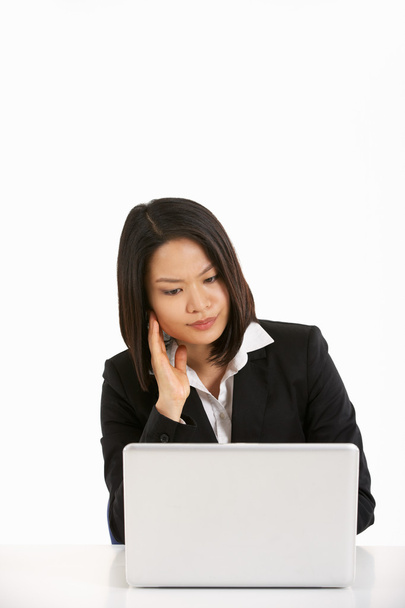 Studio Shot Of Thoughtful Chinese Businesswoman Working On Lapto - 写真・画像