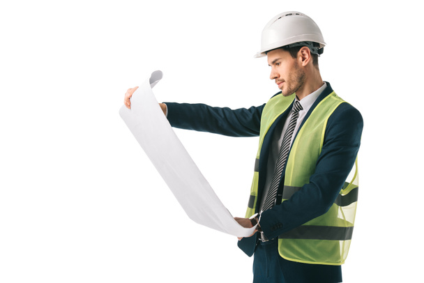 handsome male architect in helmet and safety vest looking at blueprint, isolated on white - Foto, afbeelding