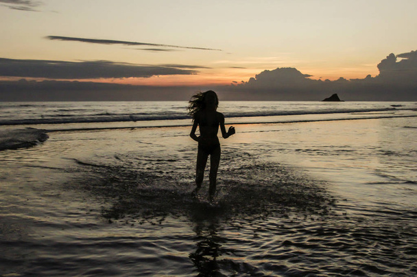 Sylwetka dziewczyna uruchomiona w tle zachód słońca na plaży - Zdjęcie, obraz
