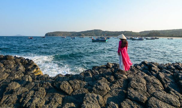 伝統的なドレス (アオザイ) 立ち、トラン, ベトナムで青い海を見ている女性. - 写真・画像