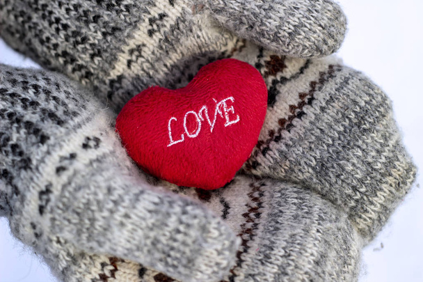 The girl in mittens holding a heart with the inscription LOVE - Photo, Image