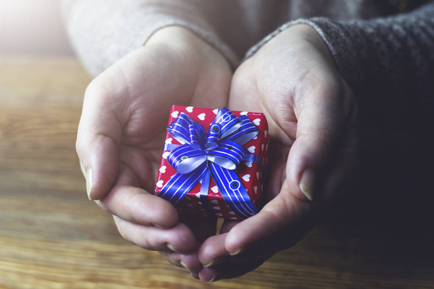 Woman gives a beautiful gift box with blue ribbon - Photo, Image