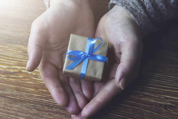 Woman holding a gift box with a blue ribbon - Photo, Image