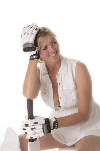 Cricketspielerin in einem entlarvenden Kleid sitzt mit ihrer behandschuhten Hand auf dem Kopf - Foto, Bild