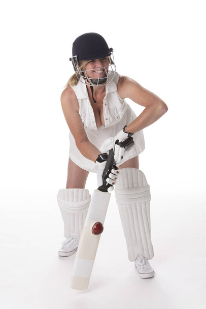 Cricketspielerin im weißen Kleid mit Schutzhelm, Schienbeinschoner, Schläger und Ball. - Foto, Bild
