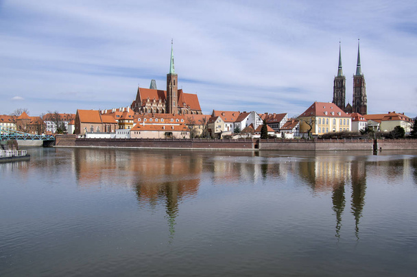 Ostrow Tumski, Wroclaw /  Poland - March 30, 2018: Odra river with Cathedral of St. John the Baptist and Collegiate Church of the Holy Cross and St. Bartholomew water reflections, touristic attraction. - Valokuva, kuva