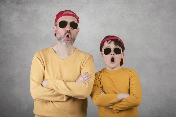 День батька, батько і син з сонцезахисними окулярами та кепкою на сірому фоні
 - Фото, зображення