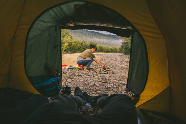 Çift doğa dinlenme. kamp. kamp ateşi üzerinde yemek. çadırdan görüntülemek - Fotoğraf, Görsel