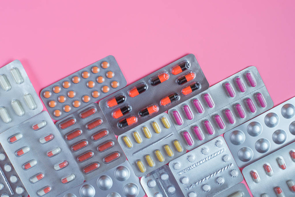 Pillen in blaren op een roze achtergrond. Ruimte voor tekst kopiëren - Foto, afbeelding