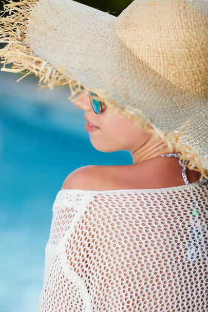 Fashion beautiful woman on summer vacation relaxing at luxury resort spa poolside. Young fashionable lady wearing sun hat  - Photo, image