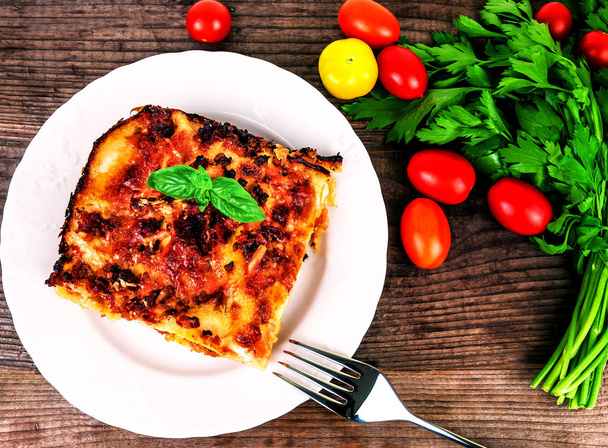 delicious lasagna and vegetables on white plate - Photo, Image