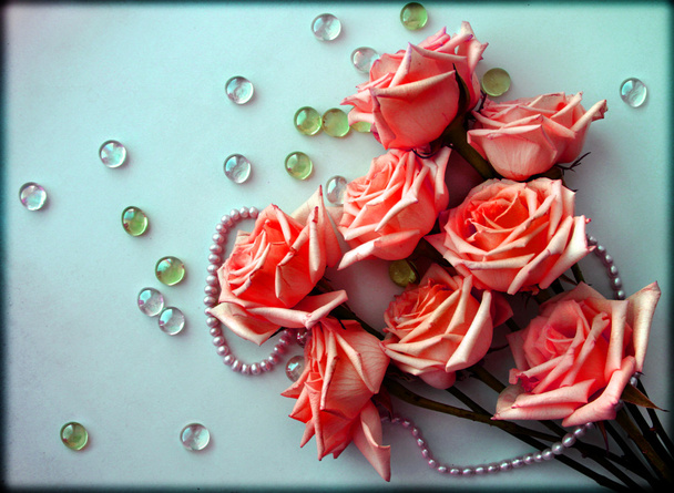 Pink Roses flowers with a pearl bead thread on light blue background with glass balls - Photo, Image