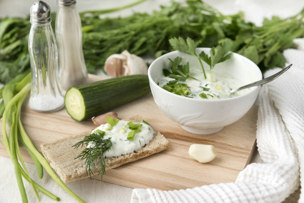 Greek yogurt salad with herbs, cucumber and spices, tzaziki, bread, cutting Board - Foto, Bild
