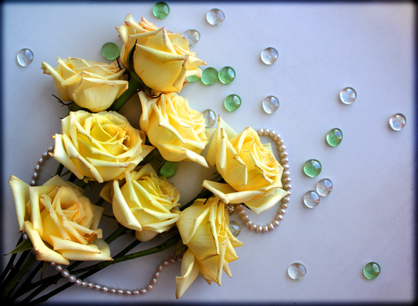 Yellow Roses flowers with a pearl bead thread on light blue background with glass balls - Foto, Bild