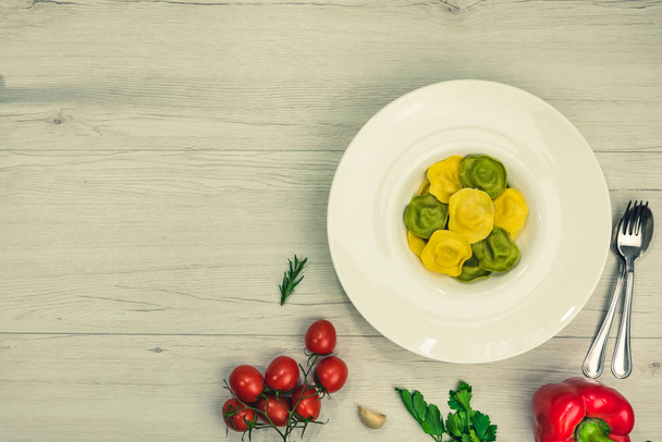 Raviolis cassic con relleno basilico y queso en un plato, sobre una mesa de madera blanca, comida vegetariana, vista superior
. - Foto, Imagen