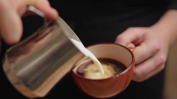 Barista pours milk in a coffee for making latte or cappuccino - Séquence, vidéo