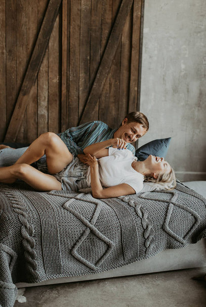 Beautiful couple in love laughs and kisses on the bed - 写真・画像