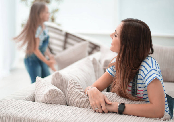 young woman sitting on sofa and looking into spacious living room.photo with copy space - Foto, imagen