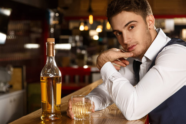 Nevadí, když se přidám? Záběr z atraktivní mladý muž dívá do kamery, svůdně sedí u baru se napít whisky  - Fotografie, Obrázek