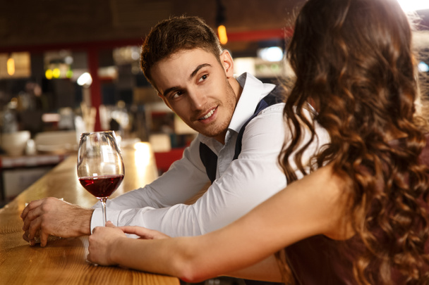 Она привлекла его внимание. Портрет красивого мужчины, слушающего свою девушку во время свидания в баре
 - Фото, изображение