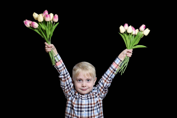Pequeno menino loiro segurando dois buquês de tulipas. Retrato. Isolar em fundo preto
 - Foto, Imagem