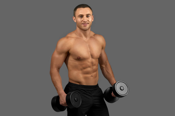 Sexy man with muscular torso posing, holding dumbbells. - 写真・画像