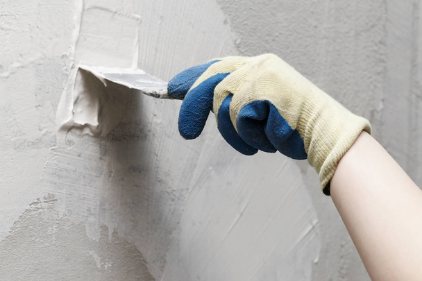 girl in blue gloves. review only a limb. putty putty on the wall. close-up. - Foto, imagen